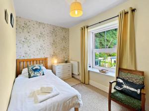 a bedroom with a bed and a window and a chair at Seagulls Rest Minehead in Minehead