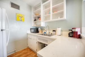 a kitchen with white cabinets and a sink at Oceanfront Condo, Private Patio, Beach Access, Sunset Views in Carlsbad