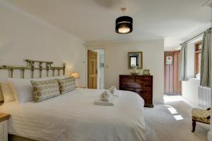 a bedroom with a large white bed and a dresser at Two Grooms Cottage Dunster in Dunster