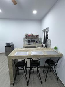a kitchen with a large island with four bar stools at Los Agaves Lto in Loreto +5 photos