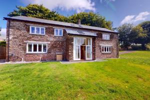 a brick house with a grass yard in front of it at The Wool Barn Simonsbath in Exford