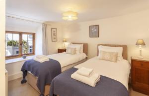 a bedroom with two beds and a window at Pebble Cottage Dunster in Dunster
