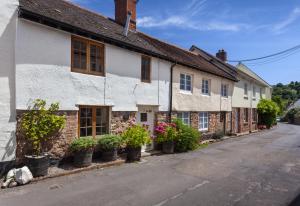 an old building with potted plants on the street at Pebble Cottage Dunster in Dunster
