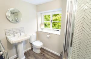 a bathroom with a toilet and a sink and a window at Trinity Cottage Roadwater in Nettlecombe +21 photos