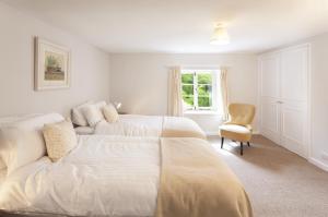 a white bedroom with two beds and a chair at Trinity Cottage Roadwater in Nettlecombe