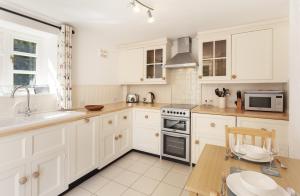 a kitchen with white cabinets and a stove top oven at Horner Cottage Luccombe in Minehead