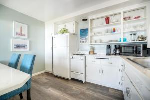a kitchen with white cabinets and a white refrigerator at Oceanfront Apartment, Private Balcony, Beach Access, Sunset Views in Carlsbad +18 photos