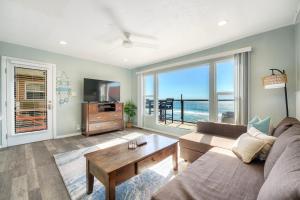 a living room with a couch and a table at Oceanfront Apartment, Private Balcony, Beach Access, Sunset Views in Carlsbad