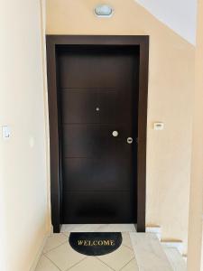 a black door with a welcome sign in front of it at Artemis apartment in Nea Peramos