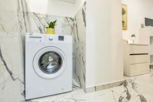 a washing machine in a white laundry room with marble walls at Kai Loft & Suite - By the Sea in Giardini Naxos