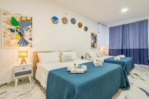 two beds in a bedroom with blue and white at Kai Loft & Suite - By the Sea in Giardini Naxos