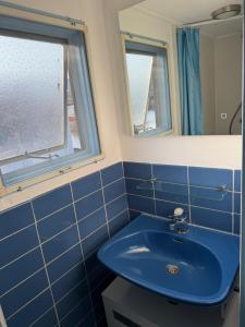 a bathroom with a blue sink and two windows at Floating Hideaway in Leimuiden +12 photos