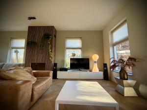 a living room with a couch and a tv at Luxe vakantievilla met jacuzzi in Zeewolde