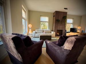 a living room with two chairs and a couch at Luxe vakantievilla met jacuzzi in Zeewolde +30 photos
