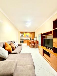 a living room with a couch and a flat screen tv at Renaissance Sunrise Inn Algarve in Portimão