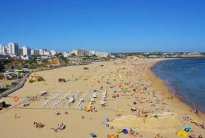 a beach with a lot of people with umbrellas at Renaissance Sunrise Inn Algarve in Portimão