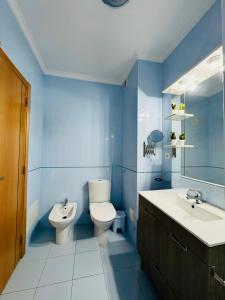 a blue bathroom with a toilet and a sink at Renaissance Sunrise Inn Algarve in Portimão +3 photos