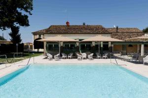 a pool with chairs and umbrellas next to a house at Villa Roncuzzi in San Pancrazio +91 photos
