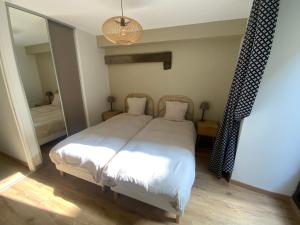 a bedroom with a white bed and a mirror at L'escapade Saint Michel in Val Couesnon