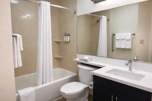 a bathroom with a sink and a toilet and a bath tub at Candlewood Suites MORGANTOWN-UNIV WEST VIRGINIA by IHG in Morgantown