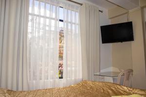 a bedroom with a window with white curtains and a television at Hotel Virgen del Carmen - Huaraz in Huaraz