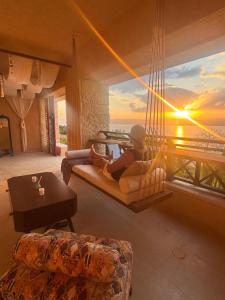 a person sitting on a swing in a living room with a sunset at Samarah EP 04 full Sea View and poll access prime location with big terrace, in Sowayma