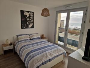 a bedroom with a bed and a view of the ocean at L'effet Mer de Stella in Stella-Plage