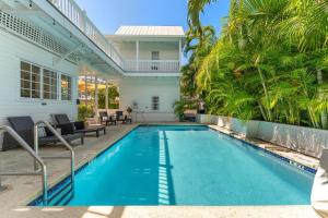 a swimming pool in the backyard of a house with palm trees at CAPTIVA at Azul Mansion Key West in Key West