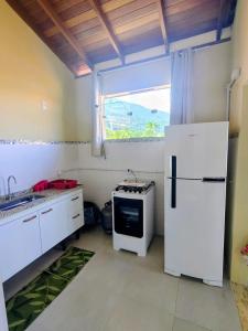 a kitchen with a white refrigerator and a window at Trindade Hospeda - Stúdios e Suítes privativos Vila Trindade in Trindade