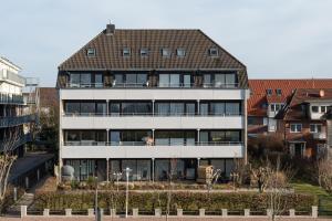 a large white building with a brown roof at Apartment Enjoy in Büsum