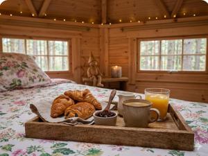 a tray of bread and croissants on a bed at La Roche aux Fées in Lapte