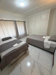 a bedroom with two beds and a tiled floor at Crest Premium in Johannesburg
