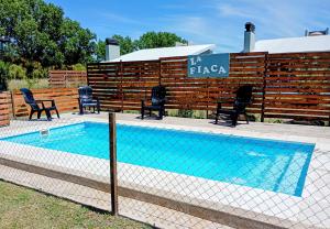 a swimming pool with chairs and a fence at Lafiaca in Sierra de la Ventana