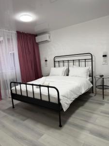 a bedroom with a black bed with white sheets and pillows at Hotel MARSO in Almaty