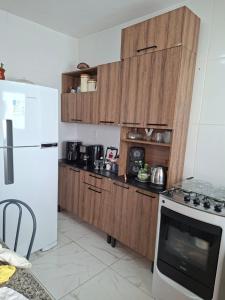 a kitchen with wooden cabinets and a white refrigerator at Aconchego em Maricá in Maricá