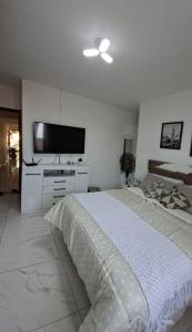 a bedroom with a bed and a flat screen tv at Aconchego em Maricá in Maricá