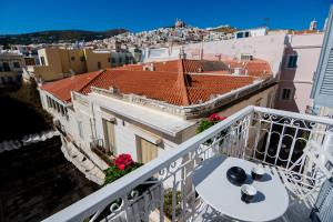 a balcony with a table and a view of a city at OIKO MINI SUITES in Ermoupoli