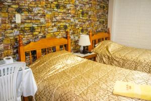 a bedroom with two beds and a brick wall at Hotel Virgen del Carmen - Huaraz in Huaraz