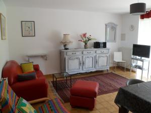 a living room with red chairs and a cabinet at Farmhouse in an amazing private park in Vannes