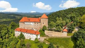 an old castle with orange roofs on a hill at Art house Tufi in Bistrica ob Sotli