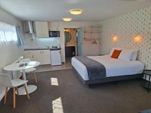 a bedroom with a bed and a table and a kitchen at RotoVegas Motel of Rotorua in Rotorua