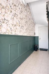 a hallway with a green wall with flowers on it at Studio cocooning in Lunel