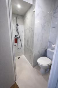 a white bathroom with a toilet and a shower at Studio cocooning in Lunel