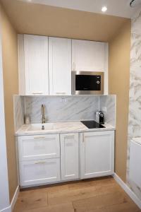 a white kitchen with a sink and a microwave at Studio cocooning in Lunel