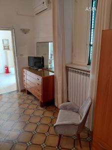 a room with a chair and a dresser and a television at Dimora Benedetta 2 0 in Bari
