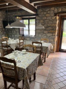 a dining room with tables and chairs and a stone wall at Posada San Tirso in Toñanes