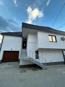 a large white house with a staircase in front of it at EFESA Apartments in Visoko