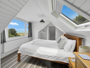 a bedroom with a bed with white sheets and windows at West Wind Porlock in Porlock