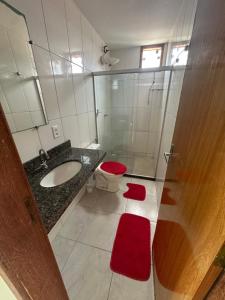 a bathroom with a sink and a toilet with red mats at Apt Pituba 500m Praia in Itacaré +9 photos