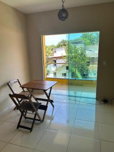 a table and a chair in a room with a large window at Apt Pituba 500m Praia in Itacaré